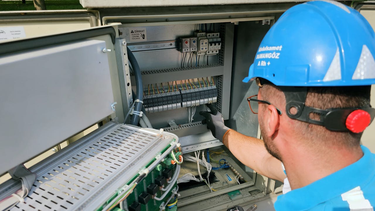An electrician works on an outdoor fusebox, ensuring safety and functionality.